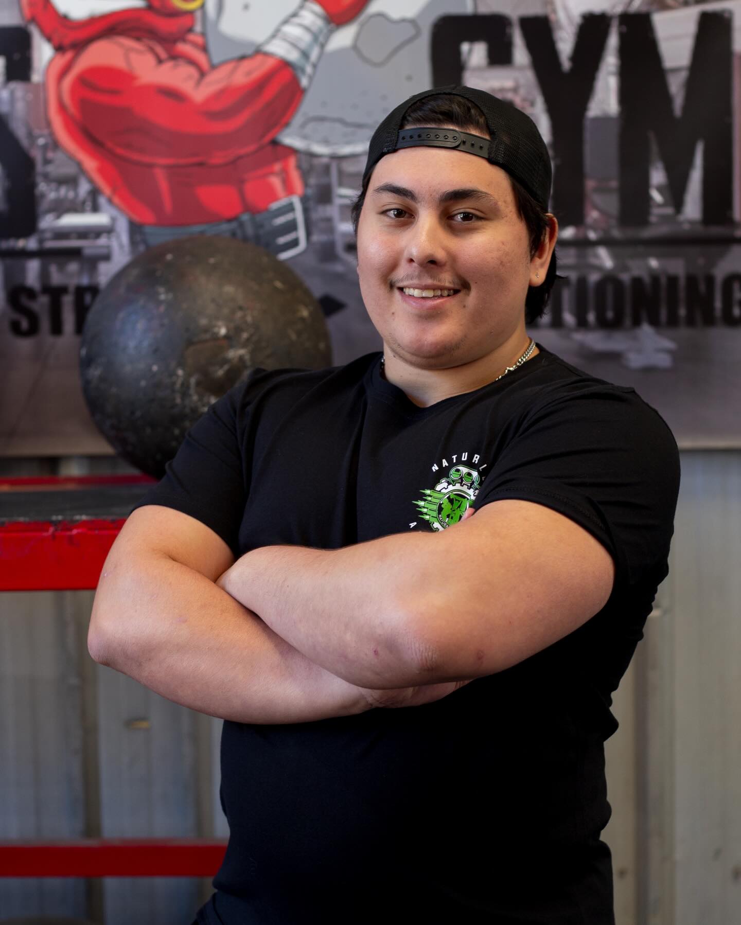 Tristan standing with his arms crossed in the gym