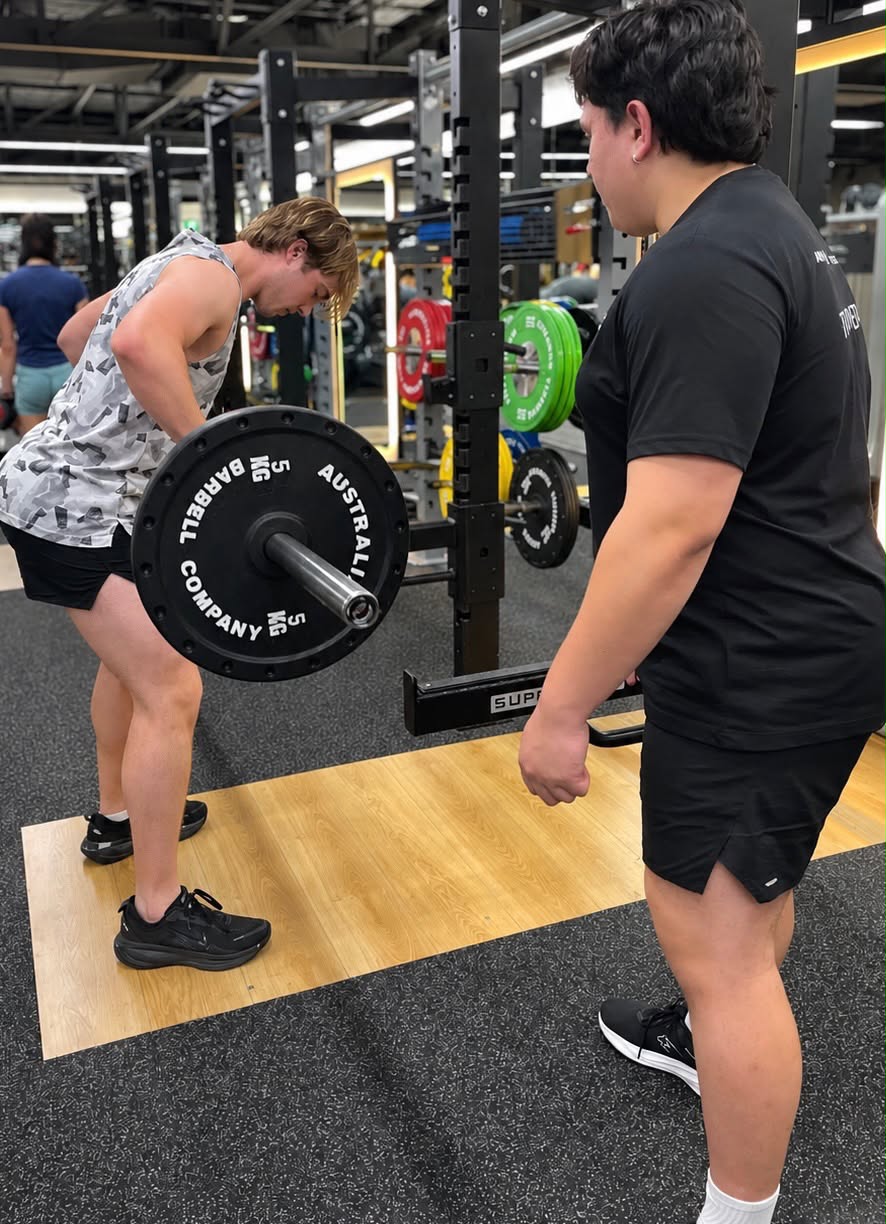 Tristan coaching a client through a barbell row